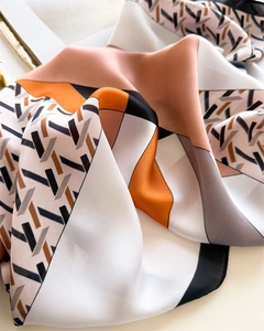 Detailed view of elegant houndstooth silk scarf with orange and pink geometric patterns