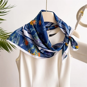 Gros plan sur un élégant foulard en satin bleu foncé noué sur une robe blanche sans manches