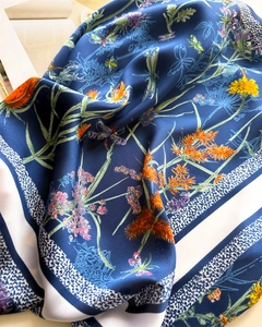 Détail d'un foulard en soie bleu marine avec imprimé floral et bord rayé