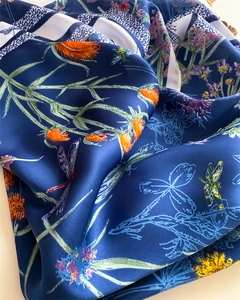 Gros plan d'un foulard en soie avec imprimé libellule et bords roulés sur tissu marine