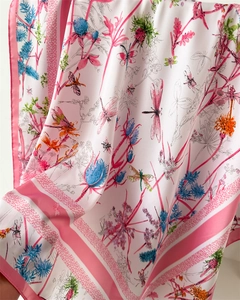 Détail d'un foulard en soie rose avec motifs de libellules et fleurs sur tissu lisse