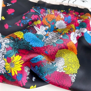 Detailed view of dark silk scarf featuring vibrant floral prints and satin texture