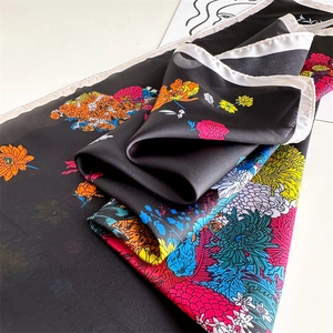 Detail of vibrant floral print on black silk scarf with elegant white rolled hem edges