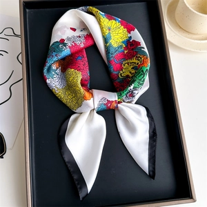 Close-up of elegant floral print satin scarf with black borders on minimalist tray