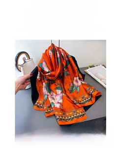 Detail of silk satin scarf with orange floral pattern draped over a black suit blazer