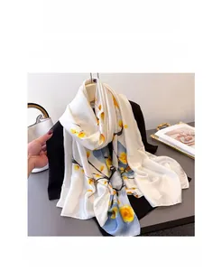 Détail d'une écharpe en soie aux motifs floraux jaunes drapée sur une veste noire