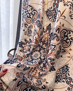 Close-up of silky satin scarf showing intricate blue and ochre paisley patterns