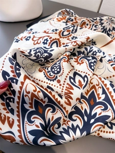 Macro shot of silk scarf detailing paisley patterns with elegant navy and orange folds