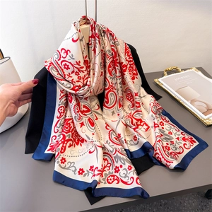 Elegant paisley floral satin scarf with blue borders displayed on a black outfit