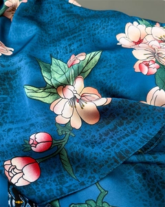 Close-up of floral print on peacock blue faux silk scarf with smooth satin texture