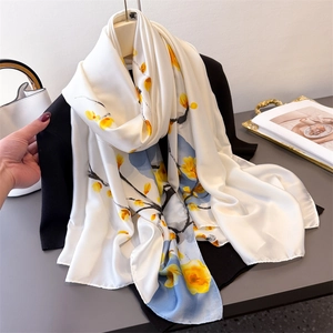 Écharpe florale en satin avec motifs de fleurs jaunes portée sur un blazer noir