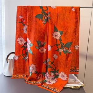 Floral print faux silk orange scarf with ethnic borders displayed on a rack