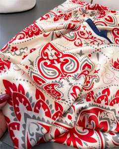 Close-up of paisley print silk scarf showing soft satin luster and fine blue hem