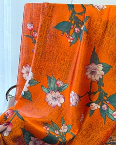 Detail of silk-like scarf featuring orange snakeskin texture and pink floral patterns