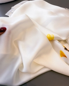 Détail macro du tissu soyeux à imprimé floral montrant la texture lisse du foulard