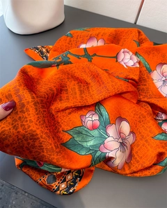 Close-up of orange silk scarf showing floral print and soft fabric texture details