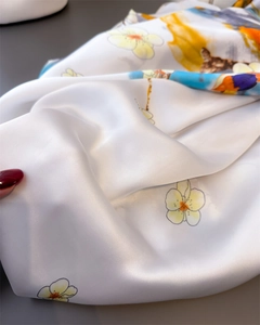 Détail d'un foulard en soie avec imprimés floraux jaunes sur fond blanc et drapé fluide
