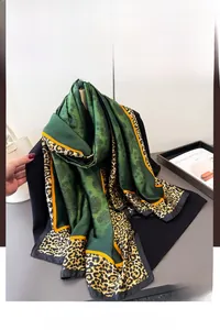 Detail of silk-like scarf featuring emerald green floral prints and leopard borders