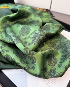 Close-up of green leopard floral print silk-like scarf with elegant satin texture and drape
