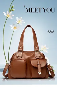 Detail van bruine leren shopper met dubbele voorzakken en metalen hartversiering