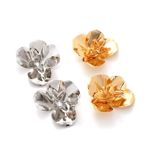 Close-up of metallic 3D flower earrings in gold and silver with layered petal details