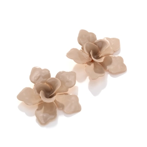 Détail de boucles d'oreilles camélia en émail beige avec des pétales multicouches chics