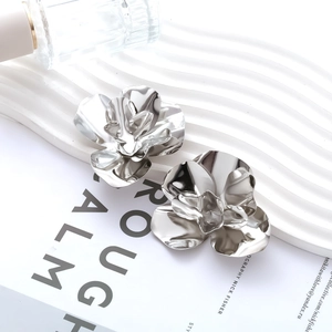 Detailed macro shot of silver floral earrings with reflective mirror finish on a tray