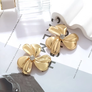 Retro golden three-petal flower earrings with center zircon on a minimalist white background