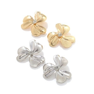 Detail of metallic three-petal flower earrings with central crystals in gold and silver