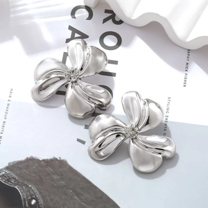 Macro detail of silver triple-petal flower earrings with a centered sparkling crystal