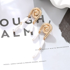 Macro shot of gold spiral textured earrings featuring white baroque pearl pendants