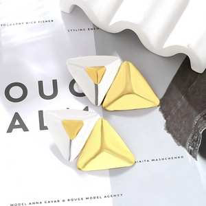 Detail view of gold and silver double-layered triangle stud earrings on fashion magazines