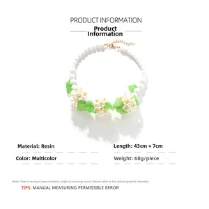 Détail du collier bohème fait main en perles avec fleurs en résine blanche et feuilles