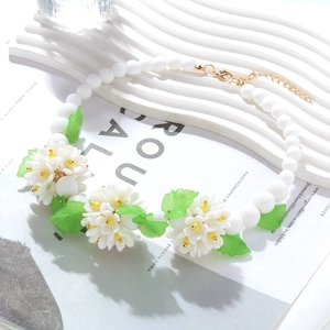 Collier bohème en perles blanches avec pendentifs fleurs et feuilles sur fond blanc pur