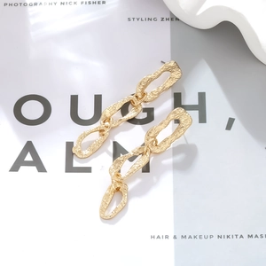 Detailed macro view of gold-toned layered geometric earrings with hammered metal texture