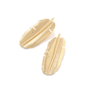 Macro detail of gold vintage banana leaf earrings with fine textured metallic finish
