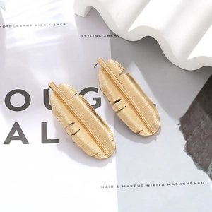Vintage gold banana leaf earrings with realistic vein texture on a fashion magazine background