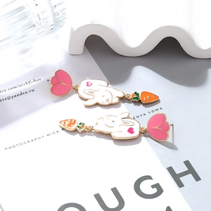 Close-up of cute asymmetric rabbit and carrot enamel drop earrings on a fashion magazine