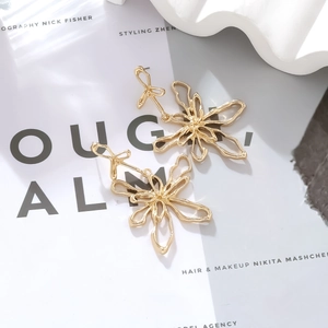 Macro view of metallic gold floral earrings with artistic irregular line details