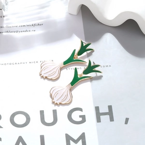 Detail of creative enamel garlic earrings with gold metal edges and green white finish