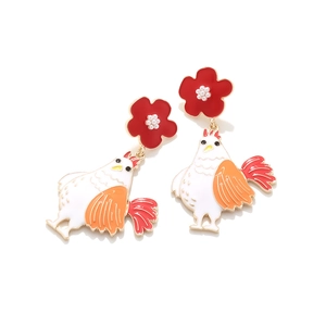 Detalle de pendientes de gallo esmaltados con flores rojas y centro de perla