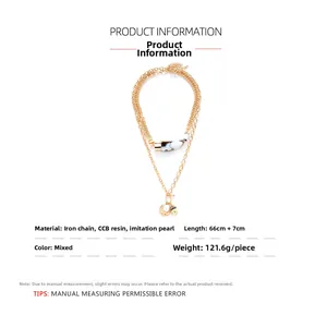 Detail of multi-layer gold chain necklace with horn pendant, faux pearl and coin charm