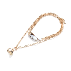 Detail of multilayer vintage gold necklace with animal horn and irregular pearl pendants