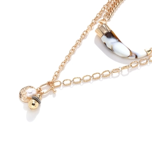 Macro view of a layered necklace with marble horn pendant and white pearl details