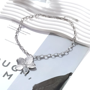 Silver alloy flower pendant necklace with textured petals on a minimalist white display