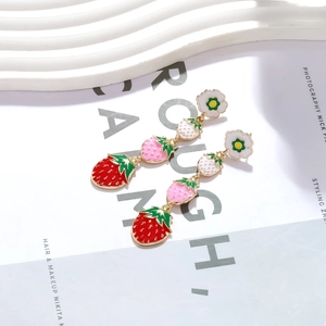 Détail de boucles d'oreilles fraise dégradées avec fleur blanche et alliage plaqué or