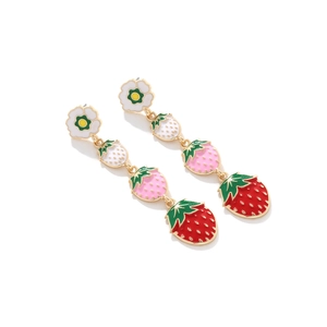 Détail de boucles d'oreilles fraises avec fleurs émaillées et breloques à dégradé rouge