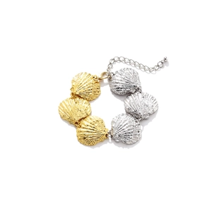 Close-up of dual-tone sea shell charms on metal bracelet with adjustable lobster clasp