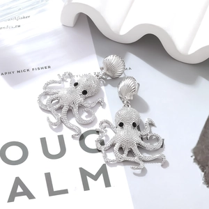 Macro detail of silver octopus earrings featuring shell studs and textured ocean pendants