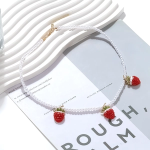 Baroque faux pearl necklace featuring three red strawberry pendants and golden clasp